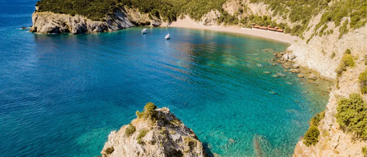 Traumhafte Bucht mit t&uuml;rkisfarbenem Wasser, Sandstrand und zwei Booten. Ein verstecktes Juwel unter den Montenegro Geheimtipps.