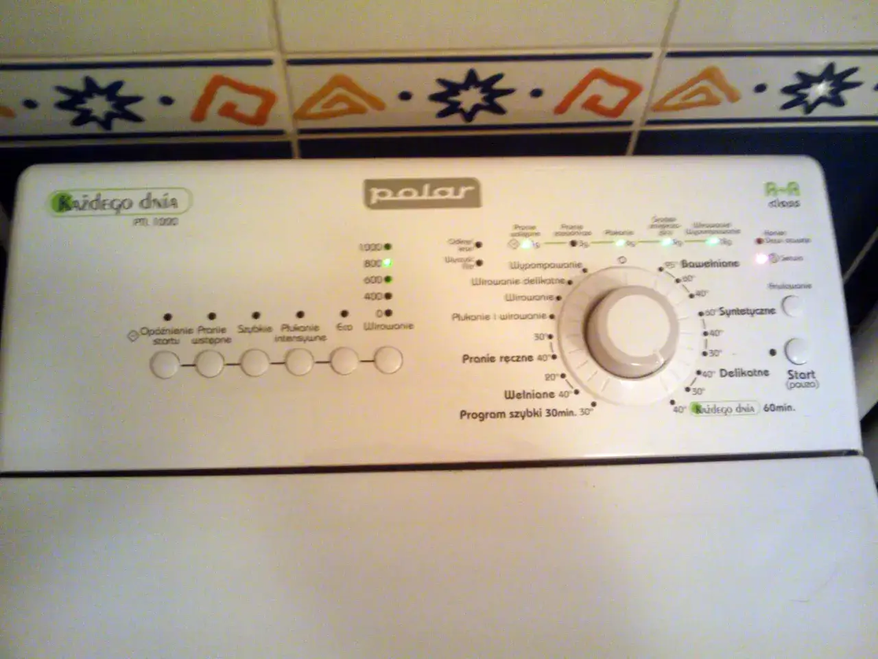 Panel sterowania pralki Polar PTL 1000. Widoczna instrukcja obsługi z programami, m.in.