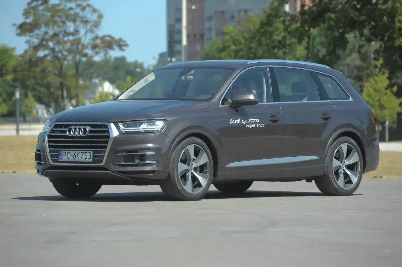 Brązowy Audi Q7 na tle drzew i budynków. Zwróć uwagę na jego imponujące audi q7 wymiary.