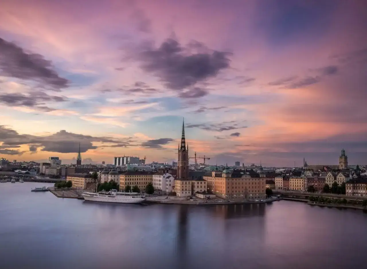 Stockholm bei Sonnenuntergang: malerische Aussicht auf die Stadt mit Kirchturm und Schiff. Entdecken Sie die Geheimtipps von Stockholm.