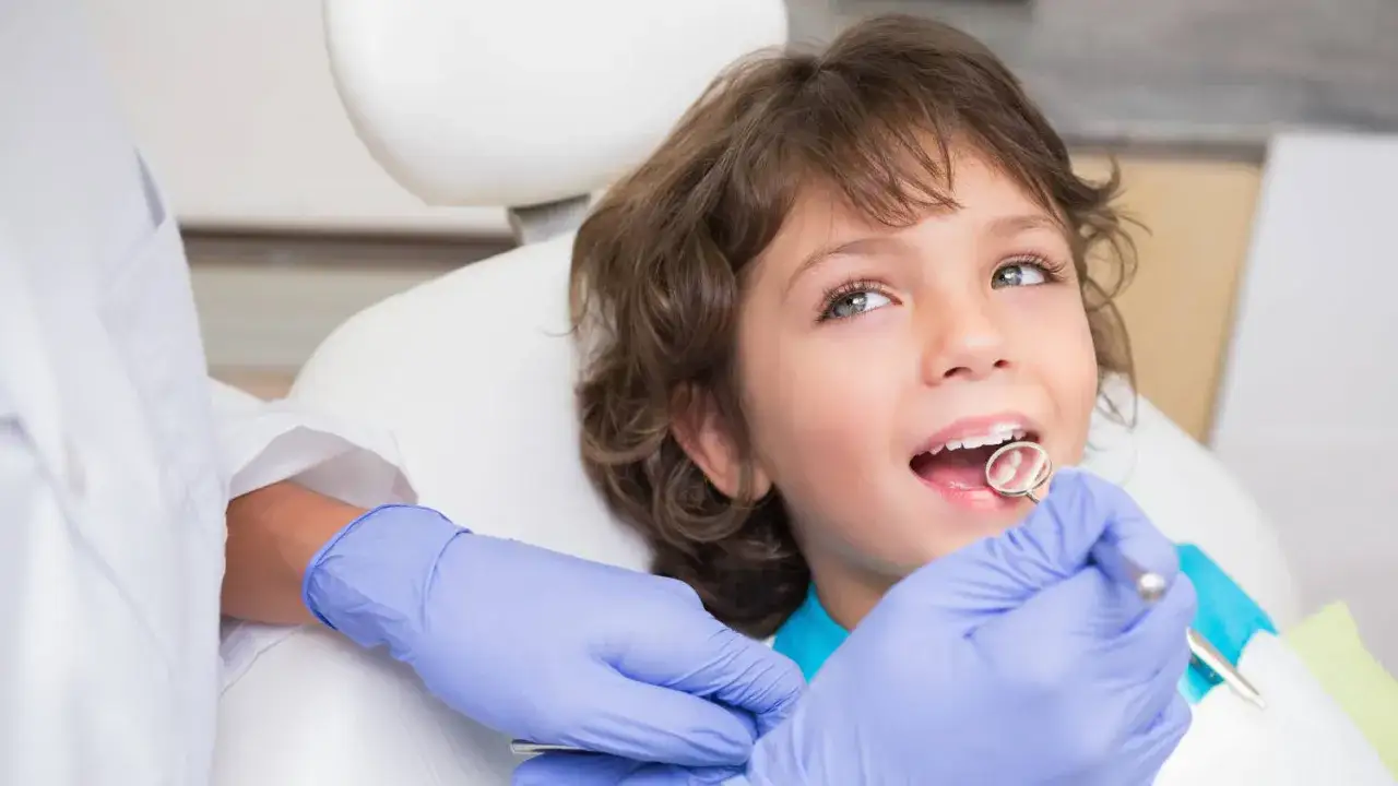 Mały chłopiec u dentysty, który bada jego zęby. Widać początki próchnicy u dziecka, ale wizyta kontrolna pomoże zapobiec dalszym problemom.