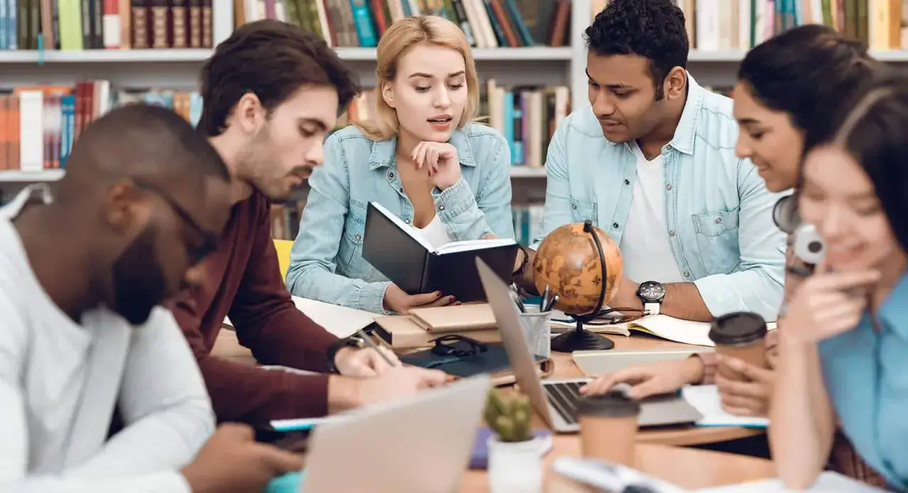 Studenten lernen gemeinsam f&uuml;r ihr **iu auslandssemester**. Ein Globus und B&uuml;cher deuten auf internationale Studienpl&auml;ne hin.