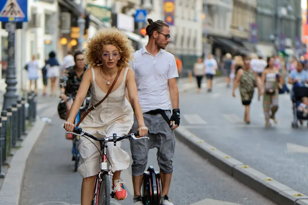 Frau auf Fahrrad, Mann auf Einrad, Menschen auf der Stra&szlig;e &ndash; ein lebendiges Bild kultureller Vielfalt in der Stadt.