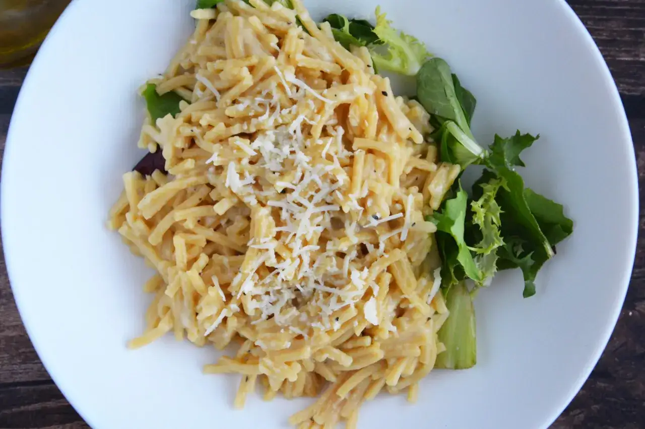 Pyszne cacio e pepe, kremowy makaron z serem i pieprzem, posypany startym parmezanem, podany z sałatką.