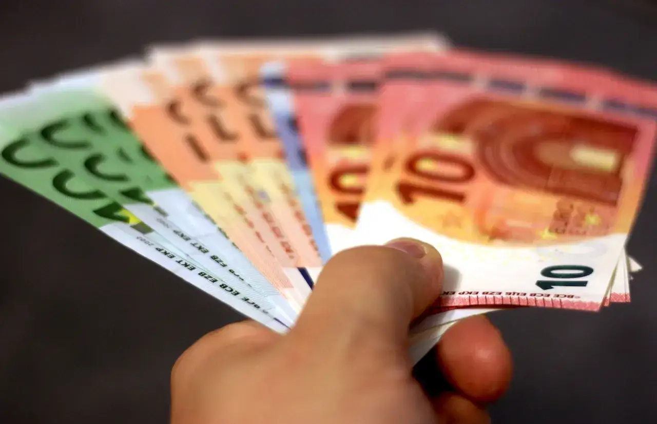 Ręka trzyma banknoty euro. Zastanawiasz się, jaka jest copywriter stawka za 1000 znak&oacute;w?