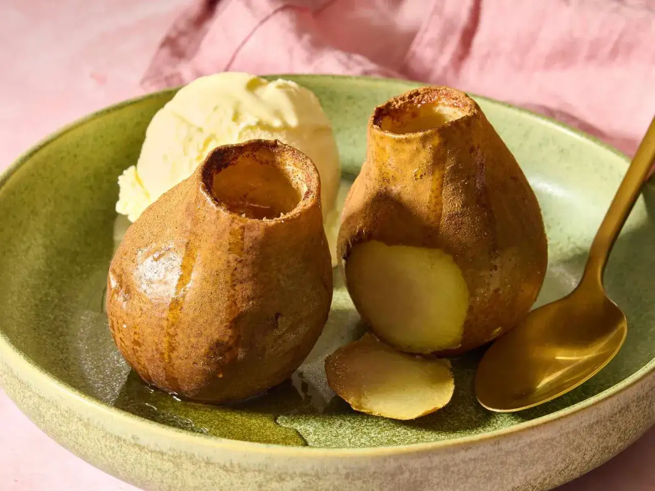Dos peras asadas al horno, tiernas y jugosas, servidas con helado de vainilla y una cuchara dorada.