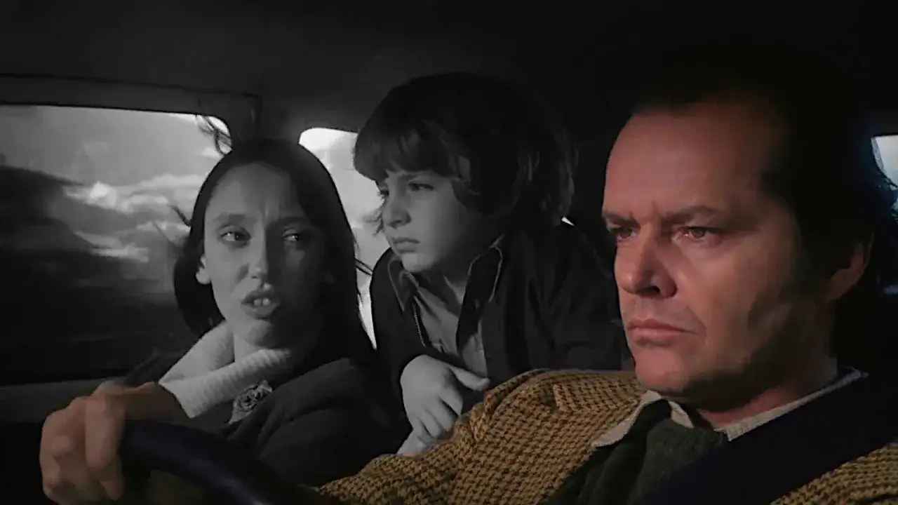 Jack Nicholson, Shelley Duvall e Danny Lloyd in auto. La tensione è palpabile, quasi a rompere la quarta parete, mentre si dirigono verso un futuro incerto.