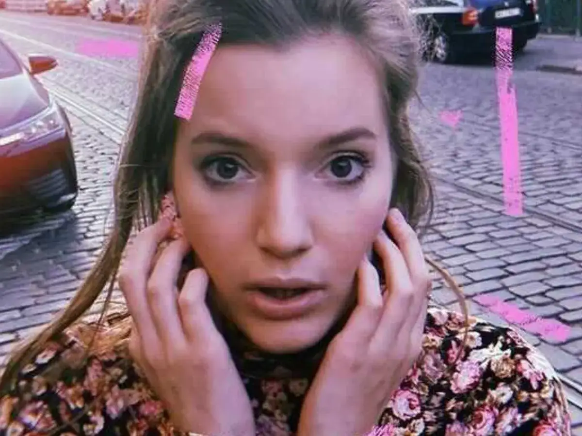 Zuzanna Jurczak, The Voice of Poland, z różowymi spinkami we włosach, na tle brukowanej ulicy i samochodów.