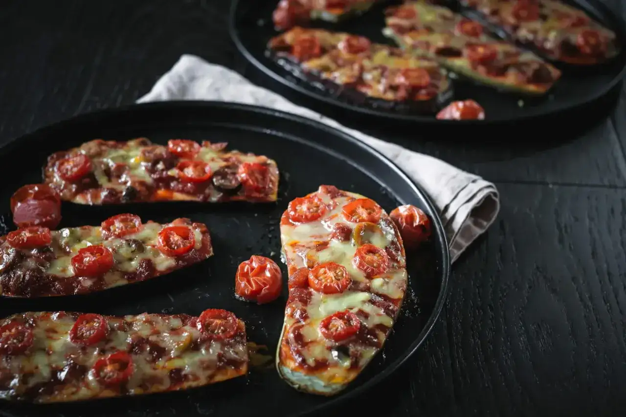 Auberginen Rezepte im Backofen: köstliche Auberginen-Hälften mit Tomaten und geschmolzenem Käse, perfekt für ein leichtes Abendessen.