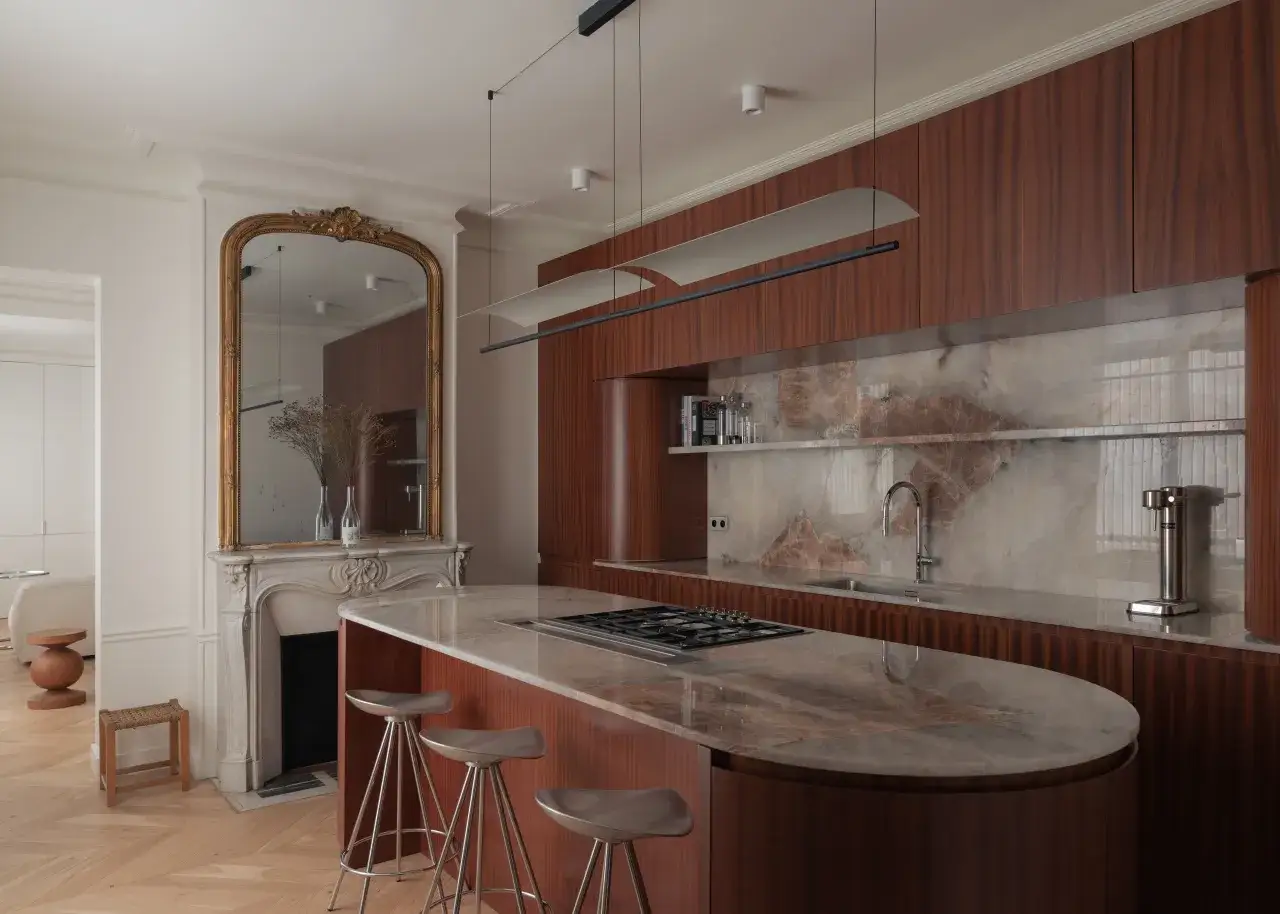 Cuisine moderne avec &icirc;lot central, plan de travail en marbre et armoires en bois. Le carrelage marron fonc&eacute; des armoires cr&eacute;e une ambiance chaleureuse.
