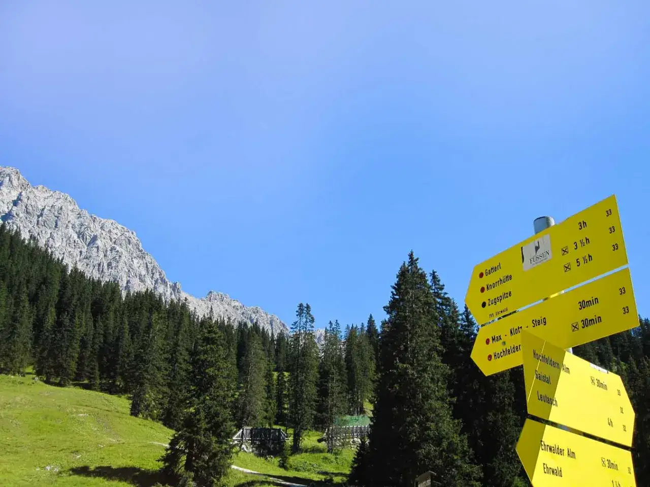Wegweiser f&uuml;r Bergwandern in Bayern: Ziel Zugspitze, Knorrh&uuml;tte, Ehrwalder Alm. Sonnenschein und klare Sicht.