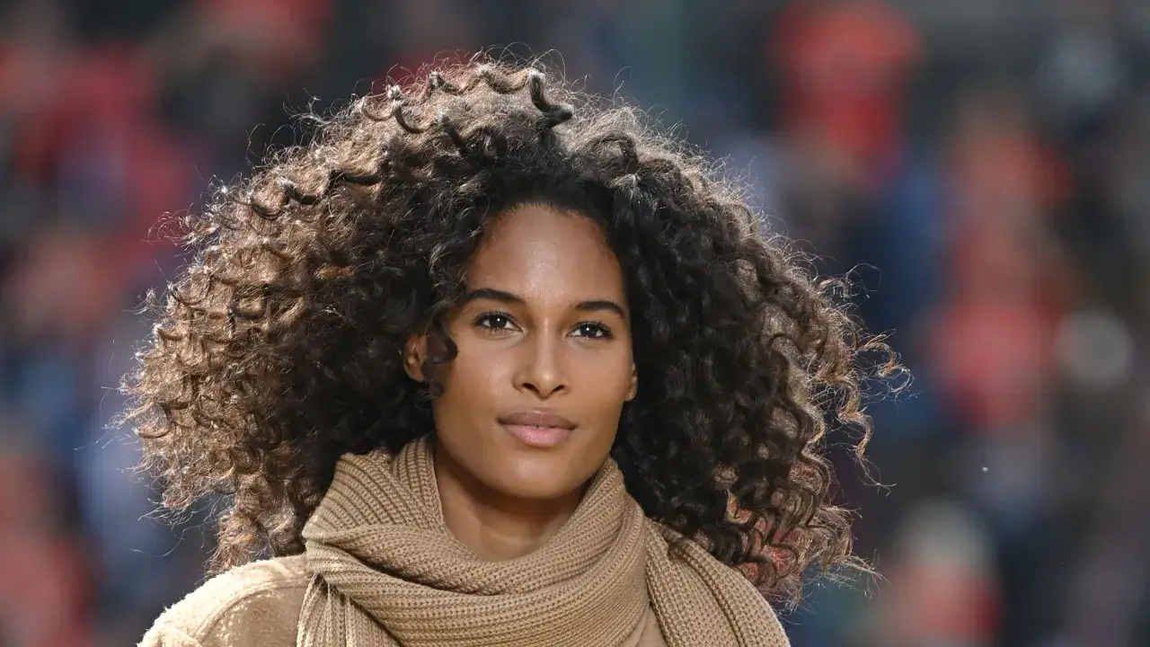 Magnifique femme avec une coupe cheveux frisés naturel, des boucles volumineuses et une écharpe en laine.