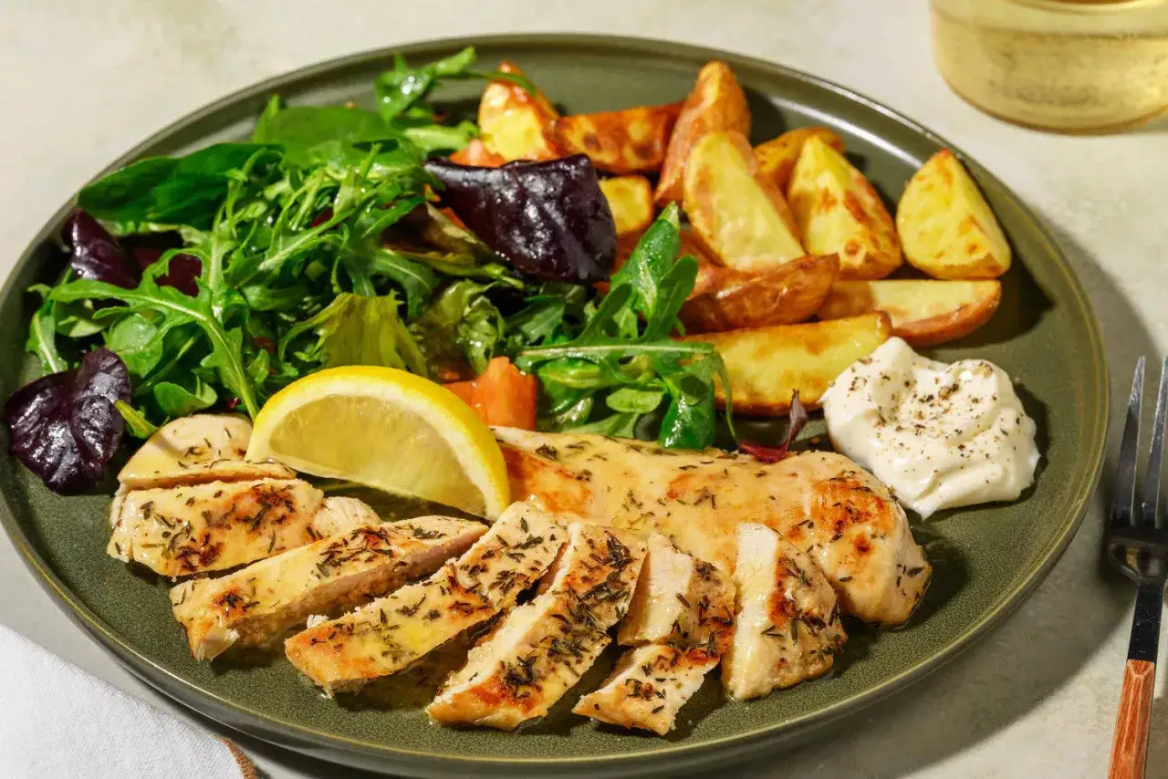 Un piatto invitante con insalata di pollo e patate arrosto, contornato da verdure fresche e una spruzzata di maionese.