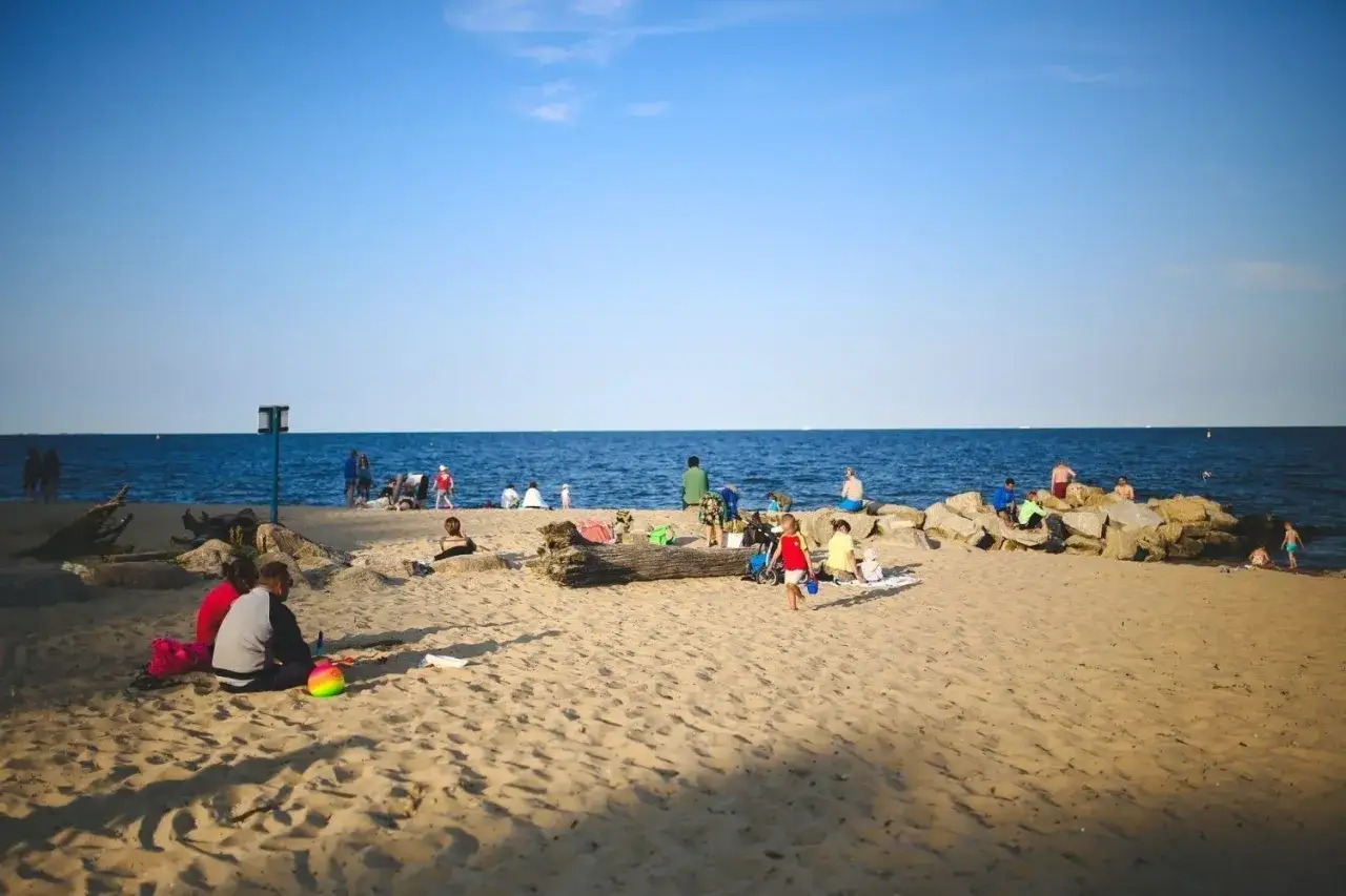 Ludzie odpoczywają na plaży, ciesząc się słońcem i morzem. To idealne miejsce na relaks, gdy zastanawiasz się, ile jest ze Szczecina do morza.