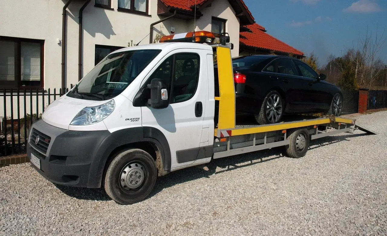 Autolaweta z czarnym Audi na pokładzie. Zastanawiasz się, jakie prawo jazdy na autolawetę? To zależy od masy pojazdu.