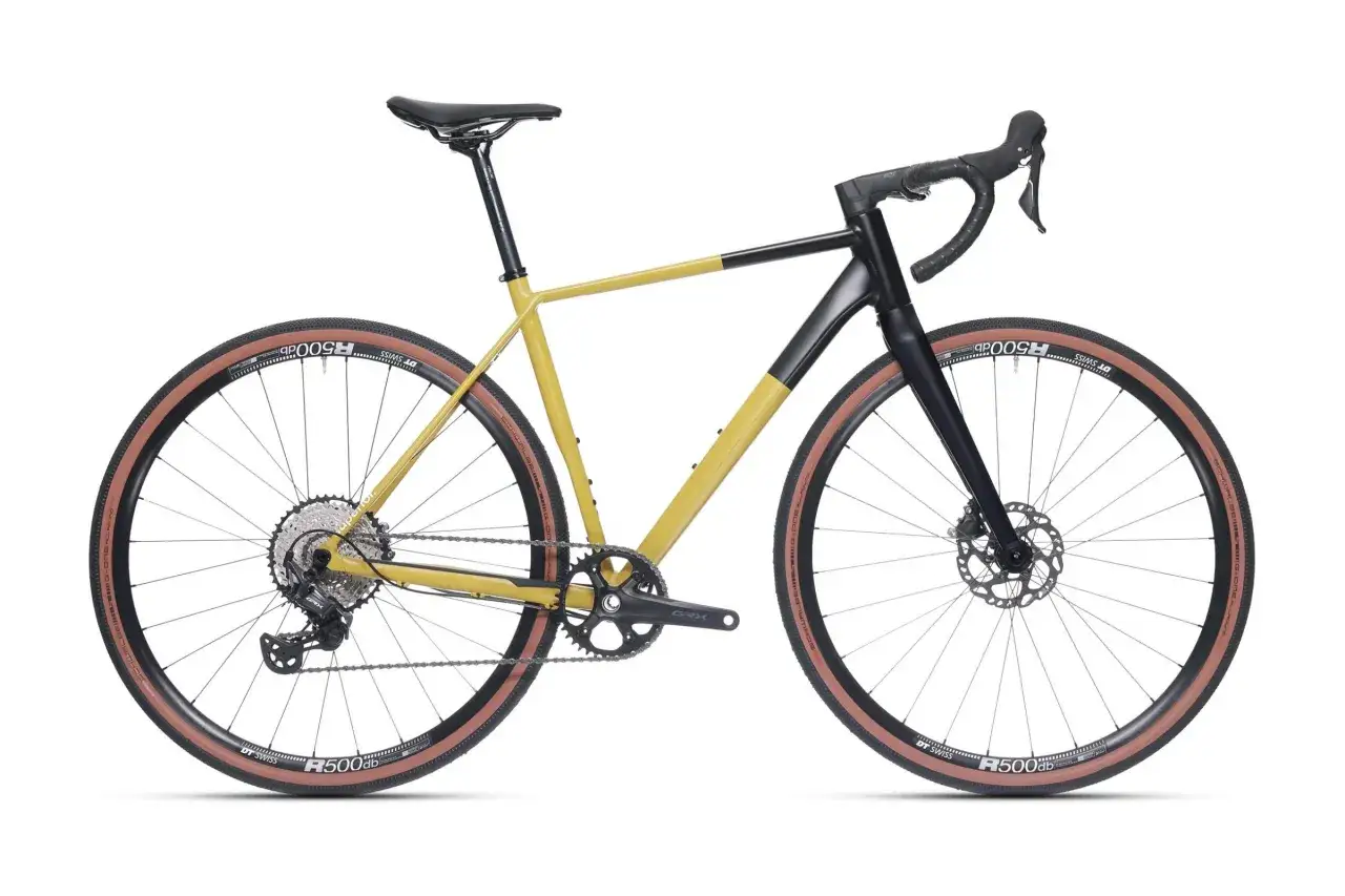 Żółto-czarny rower gravelowy z brązowymi oponami. Jego waga roweru jest idealna do długich tras.