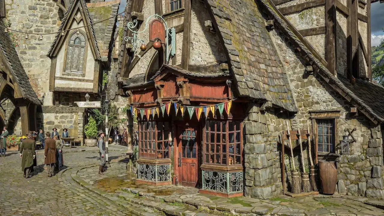 Calle adoquinada con edificios de piedra y tejados de pizarra. Gente vestida con ropa de época pasea. ¿Quién fundó Hogsmeade?