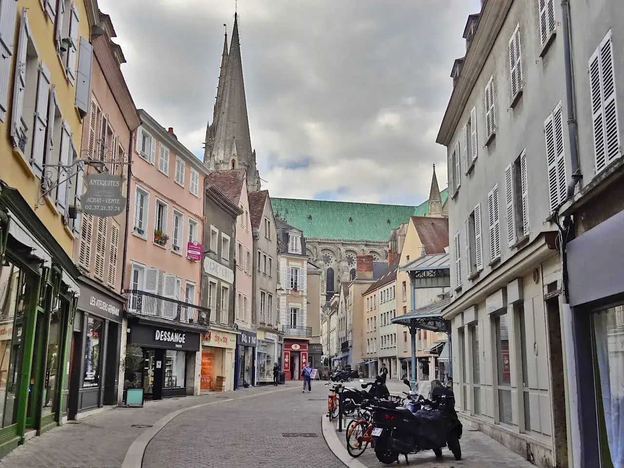 Une rue pav&eacute;e m&egrave;ne &agrave; la cath&eacute;drale de Chartres. Id&eacute;al pour visiter Chartres &agrave; pied, avec ses boutiques et ses fa&ccedil;ades color&eacute;es.