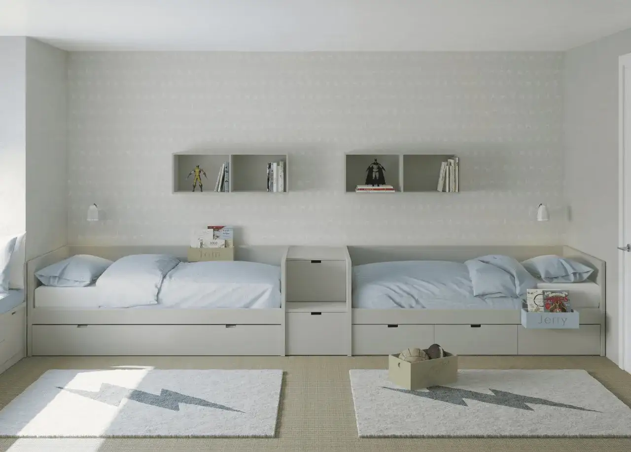 Habitaci&oacute;n infantil dividida para ni&ntilde;o y ni&ntilde;a con dos camas gemelas, separadas por un mueble central. Alfombras con rayos y figuras de superh&eacute;roes en estantes.