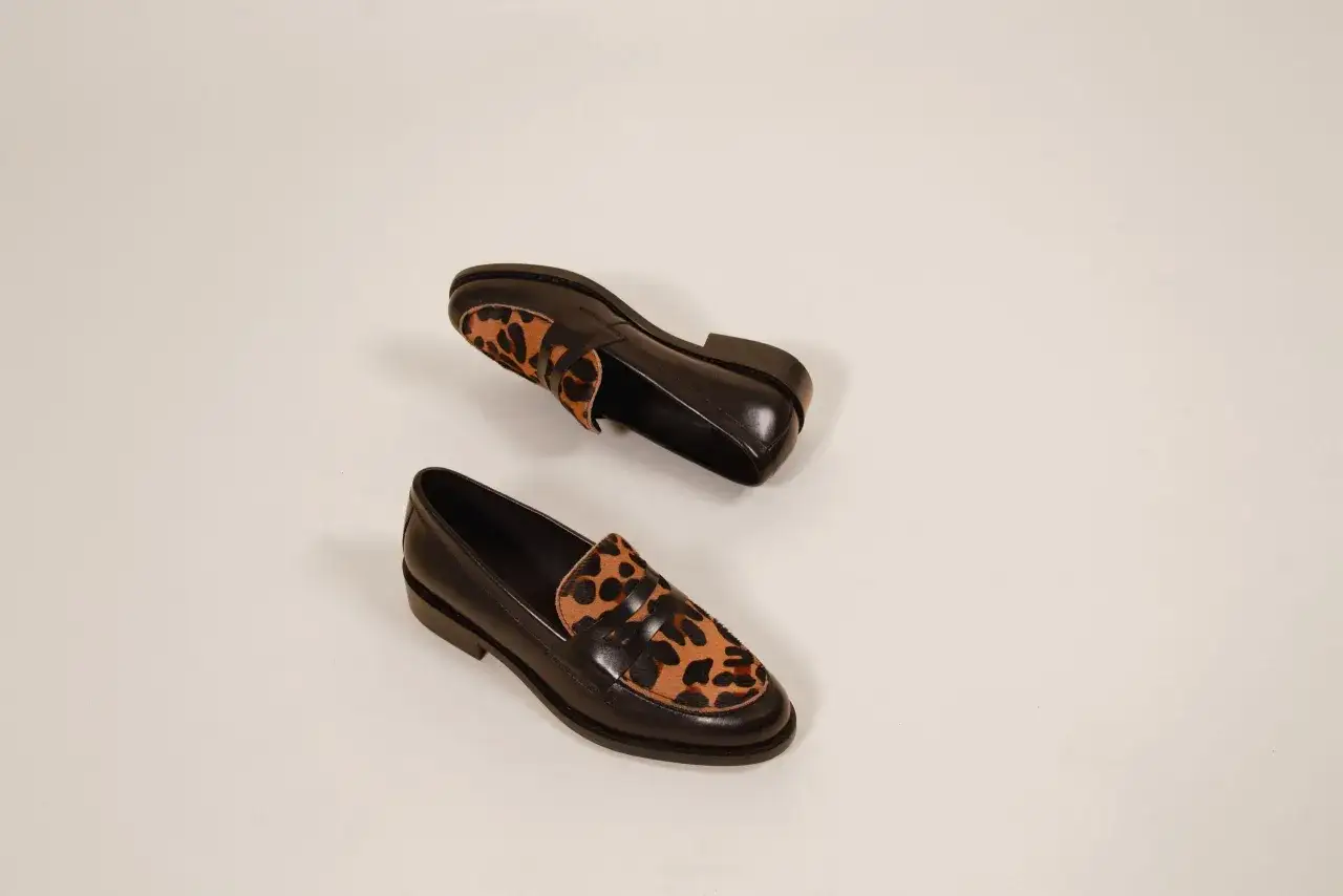 Une paire de mocassins noirs avec un empiècement léopard. Une chaussure à avoir pour un look audacieux.