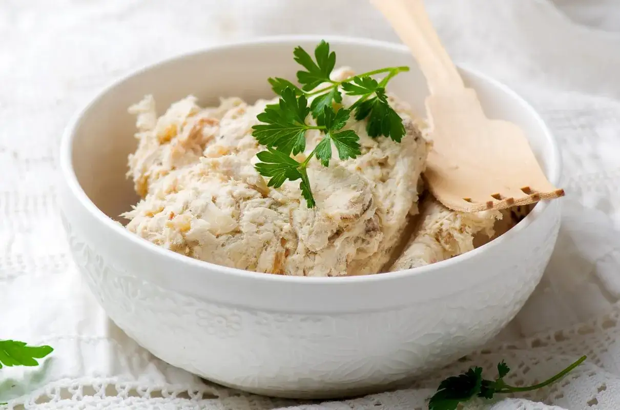 Pyszna pasta z mięsa z rosołu, idealna na kanapki. Posypana natką pietruszki, podana w miseczce z drewnianą łopatką.