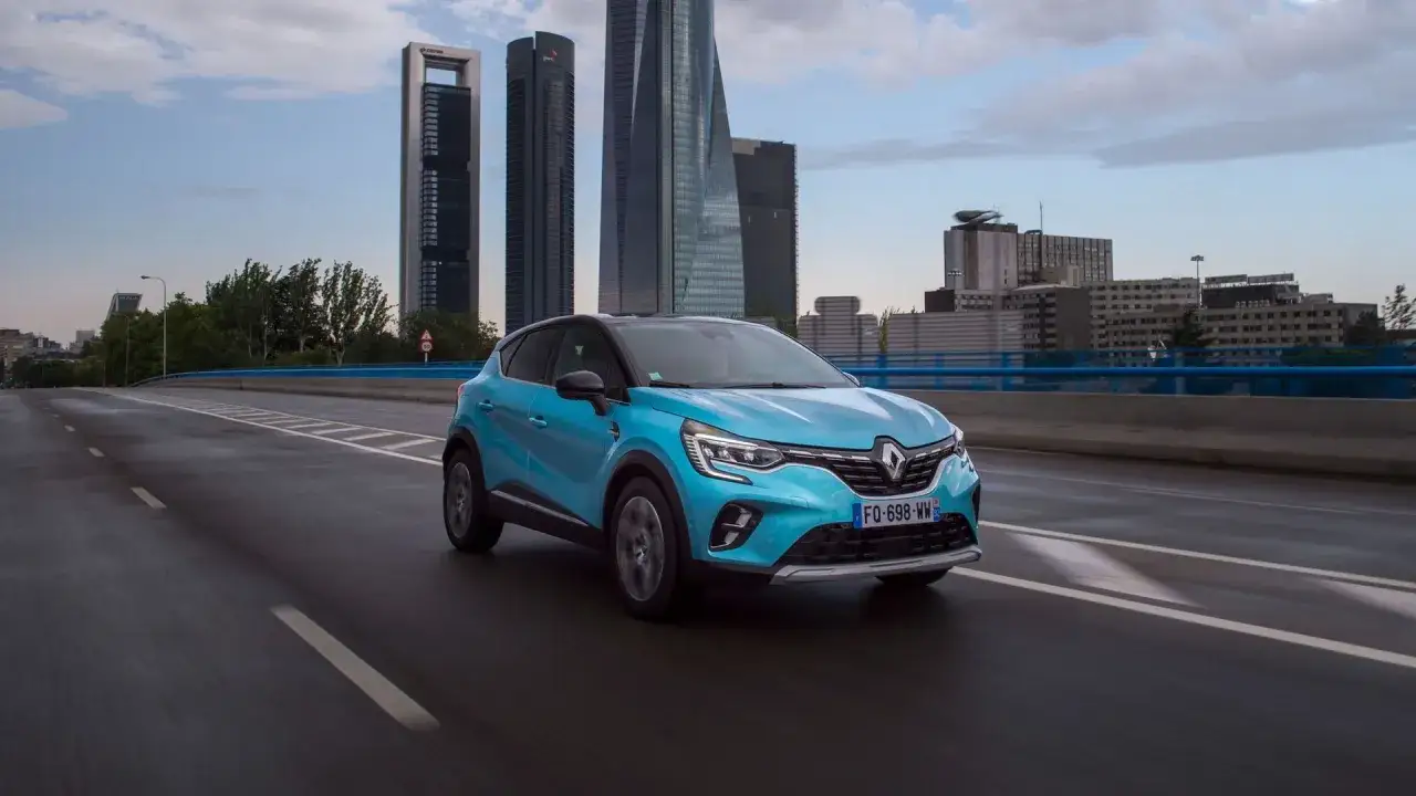 Un Renault Captur E-Tech azul circula por una autopista urbana, sorteando los problemas de la ciudad.