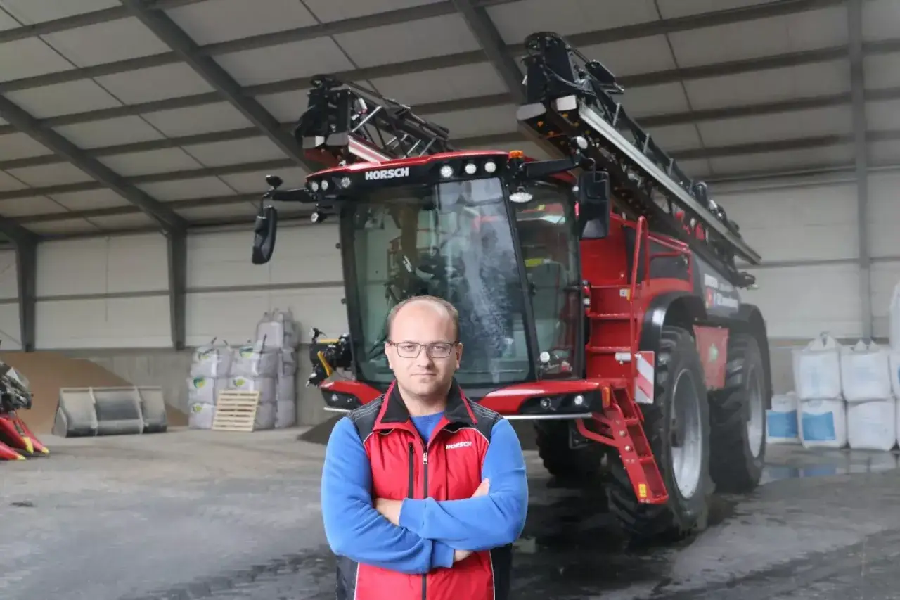 Rolnik przed nowoczesnym opryskiwaczem HORSCH. Zastanawia się, ile wody na hektar oprysku będzie potrzebne do ochrony jego plon&oacute;w.