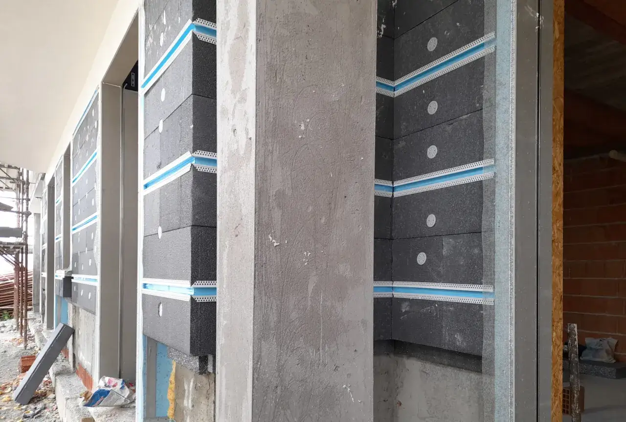 Warstwa grafitowego styropianu z niebieskimi taśmami i siatką, przygotowana do ocieplenia. Czy styropian wygłusza? To pytanie zadaje sobie wielu inwestorów.