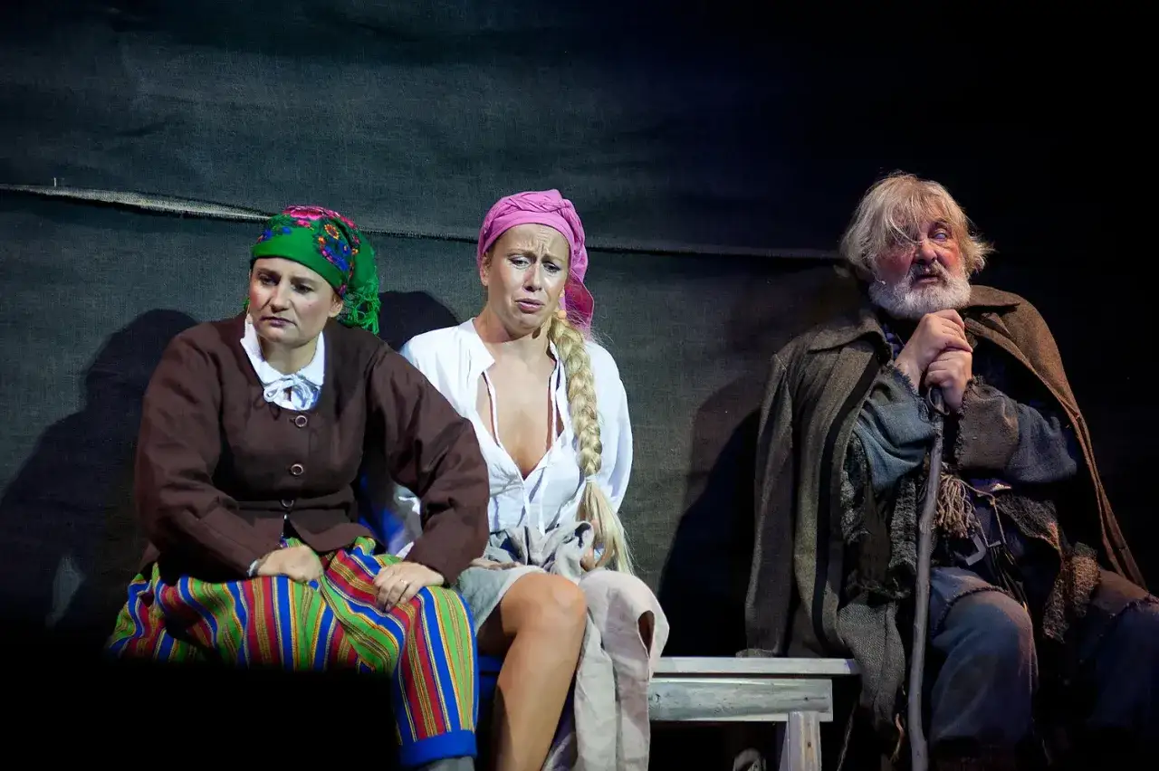Trzech aktorów w strojach ludowych na scenie Teatru Muzycznego Gdynia.
