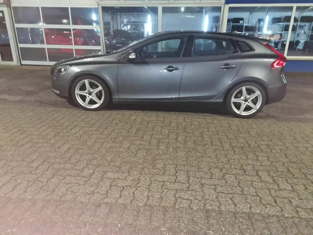 Grauer Volvo V40, der auf einem gepflasterten Hof steht. M&ouml;gliche Schwachstellen des Volvo V40 sind hier nicht sichtbar.