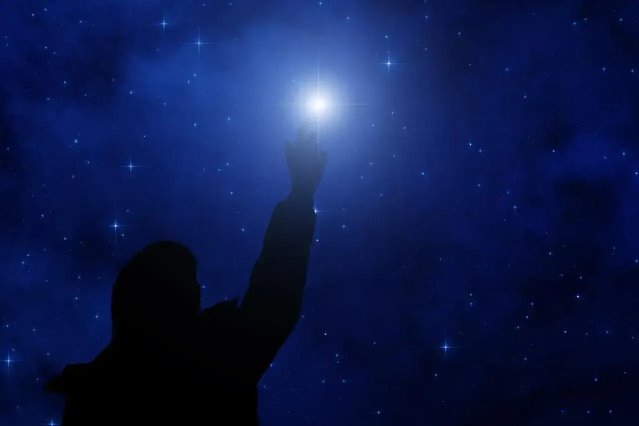 Sylwetka sięga ku jasnej gwieździe polarnej na tle nocnego, gwiaździstego nieba.
