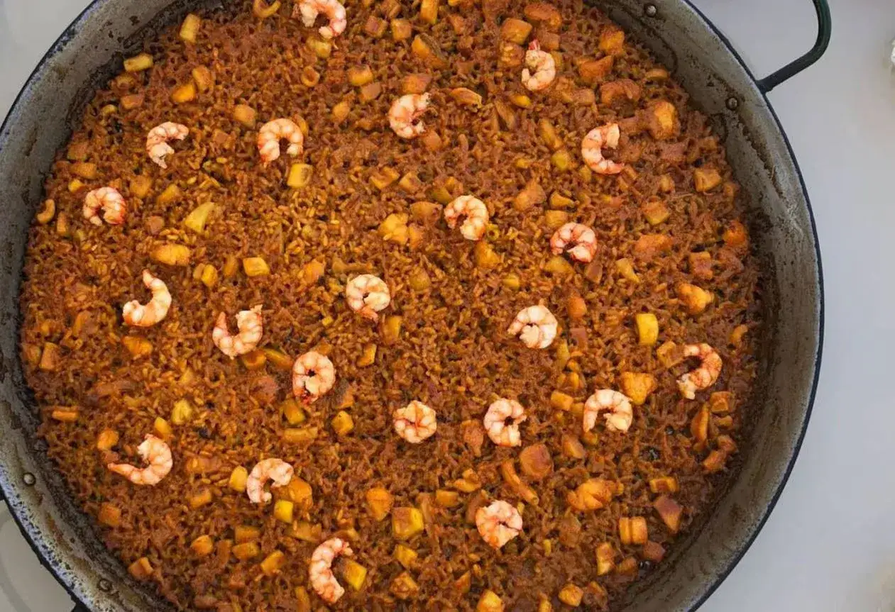 Arroz del senyoret en paellera, con gambas, trozos de calamar y otros mariscos integrados en el arroz.