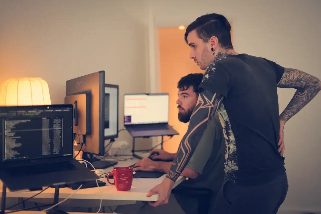 Deux d&eacute;veloppeurs Ruby on Rails collaborent sur un projet, l'un regardant l'&eacute;cran, l'autre expliquant une ligne de code.