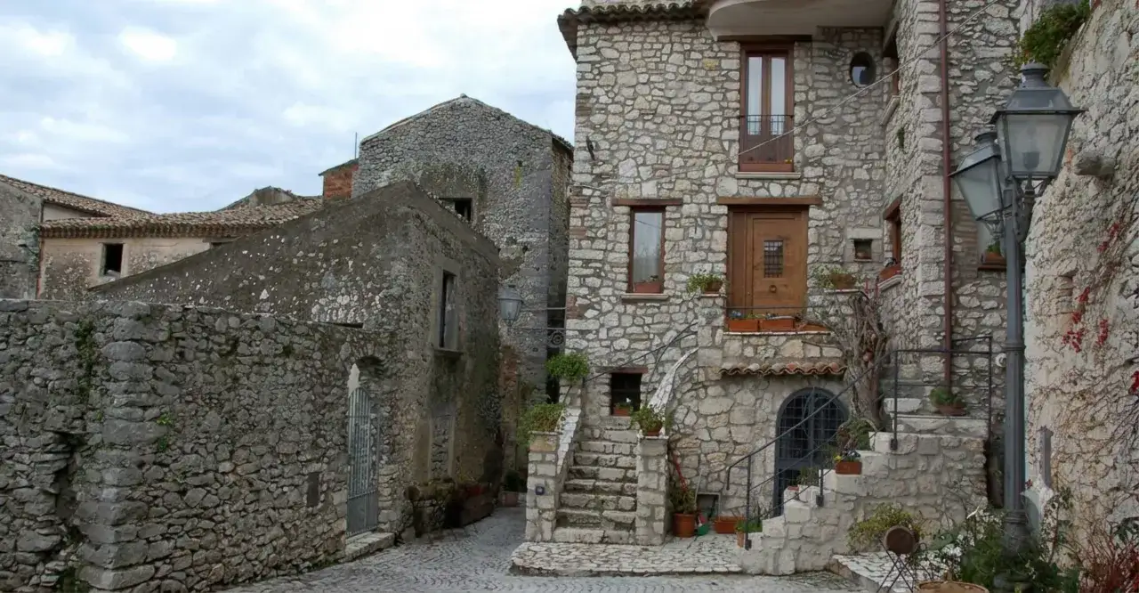 Antica via acciottolata tra case in pietra, un invito a scoprire i borghi del centro Italia da visitare.