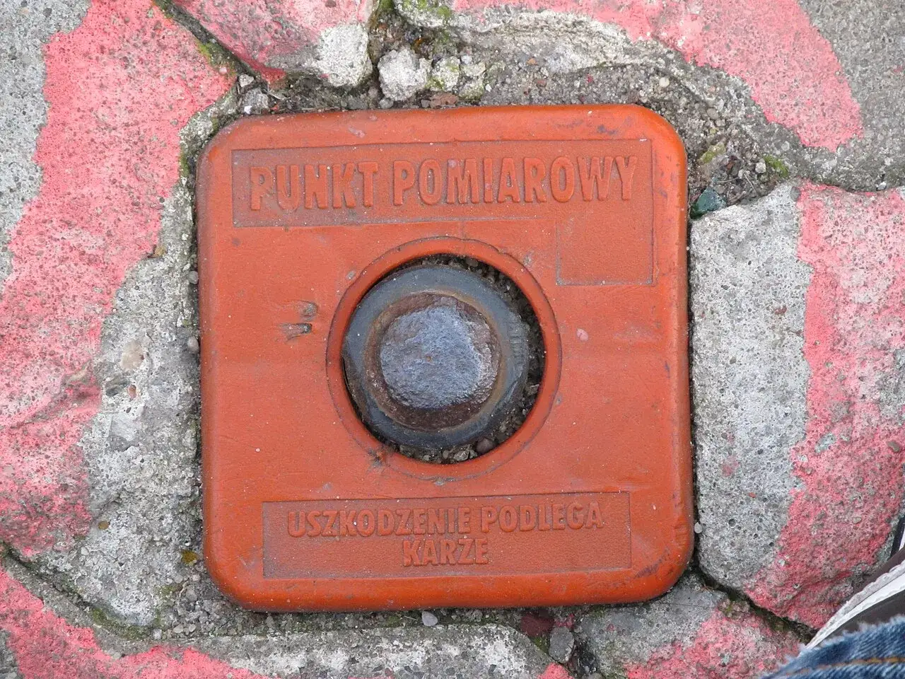 Pomarańczowy punkt pomiarowy geodety, z napisem 