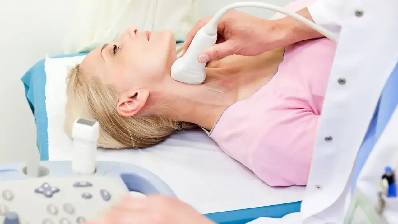 Badanie szyi pacjentki aparatem doppler. Lekarz wykonuje USG tarczycy.