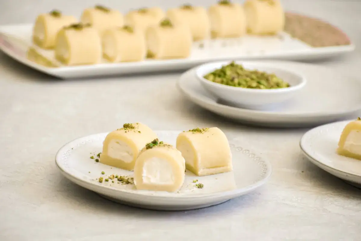 Halawet el jibn, söta rullar med krämig fyllning och strösslade pistagenötter, serveras på vita fat.