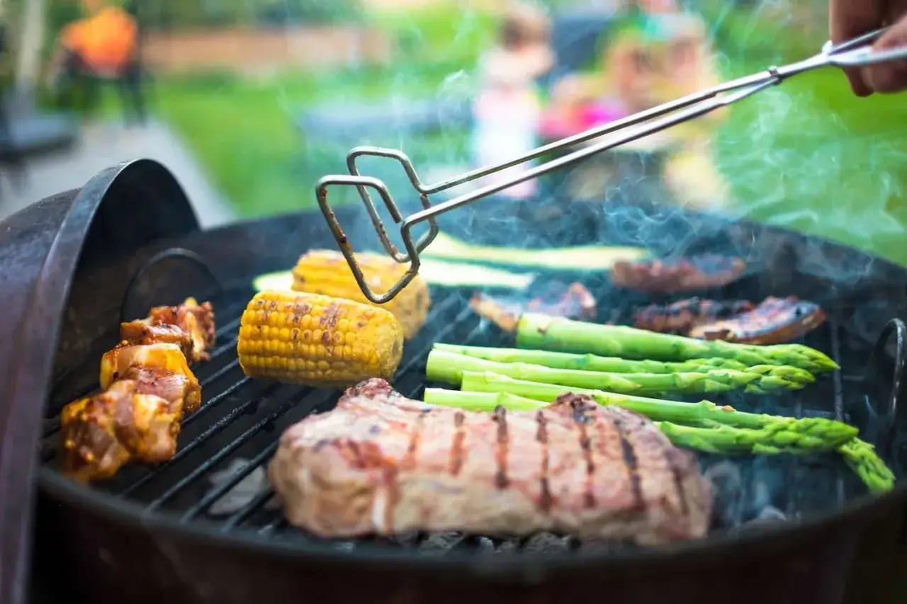 Carne, ma&iacute;z y esp&aacute;rragos cocin&aacute;ndose en una parrilla. Una gu&iacute;a visual de como hacer barbacoa.