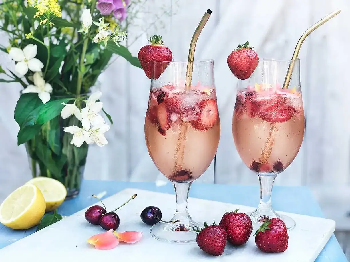 Tv&aring; glas med drinkar med gin och prosecco, fyllda med is, jordgubbar och k&ouml;rsb&auml;r. En somrig och uppfriskande dryck.