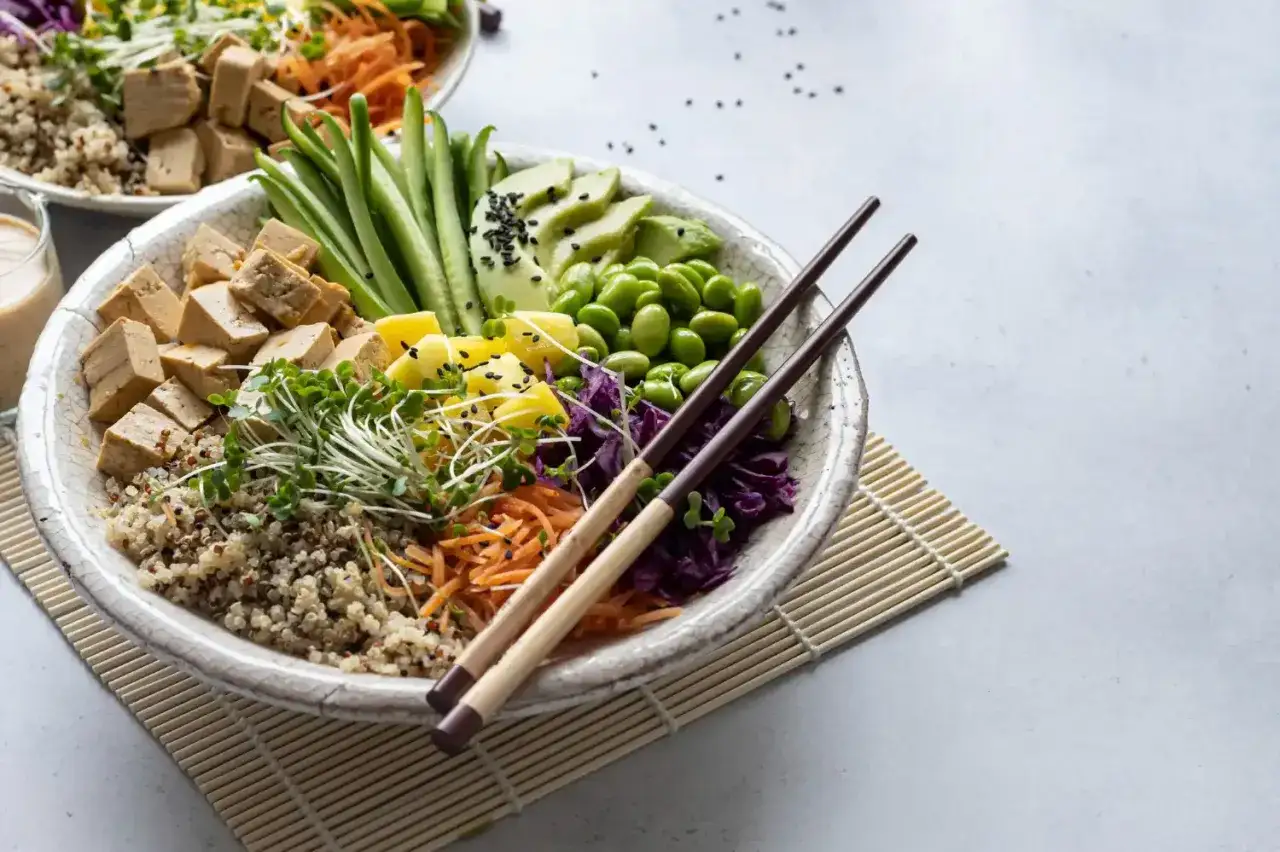Kolorowa miska pełna zdrowych składników: tofu, komosa ryżowa, edamame, awokado, marchewka, ogórek i kiełki. Tak właśnie co jedzą buddyści, ceniąc świeżość i prostotę.