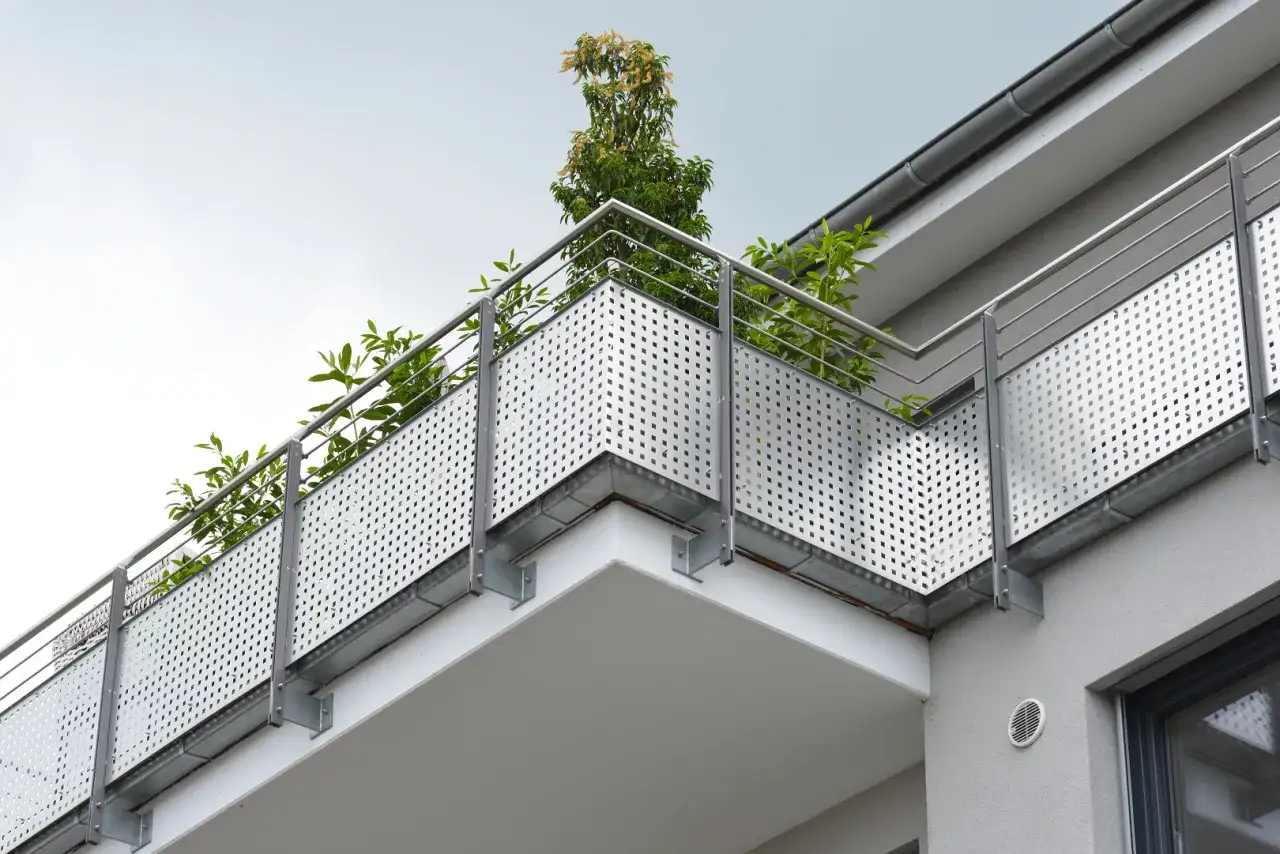 Nowoczesny balkon z ażurową balustradą i zielenią. Ocieplenie balkonu krok po kroku to dobry pomysł na poprawę komfortu.