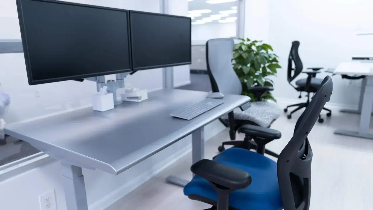 Poste de travail moderne avec double &eacute;cran, bureau r&eacute;glable en hauteur et chaises ergonomiques, id&eacute;al pour une analyse ergonomique.