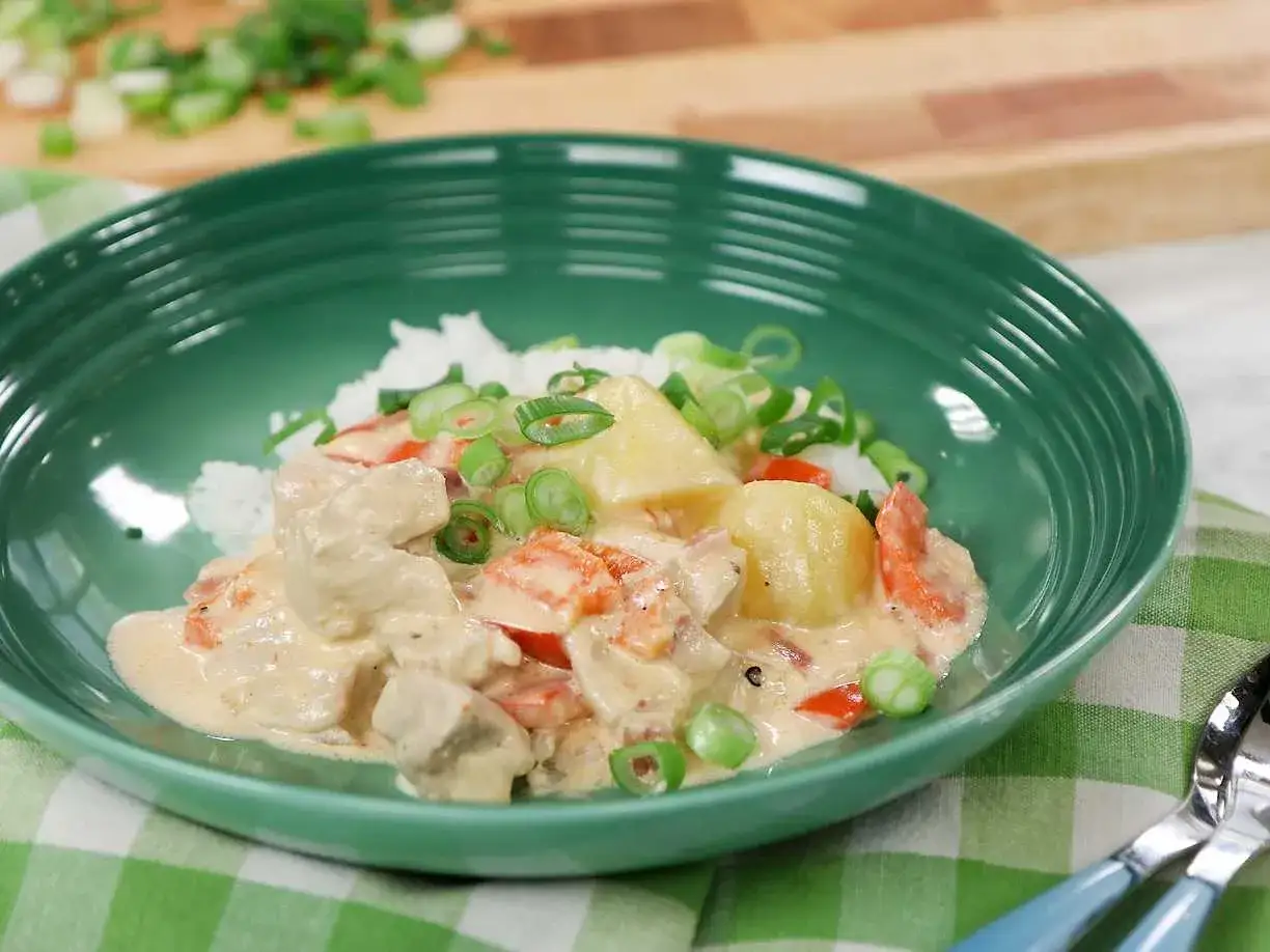 En kr&auml;mig kycklinggryta med ris, toppad med f&auml;rsk salladsl&ouml;k och bitar av ananas. En h&auml;rlig kycklinggryta med ris som ser uts&ouml;kt ut.