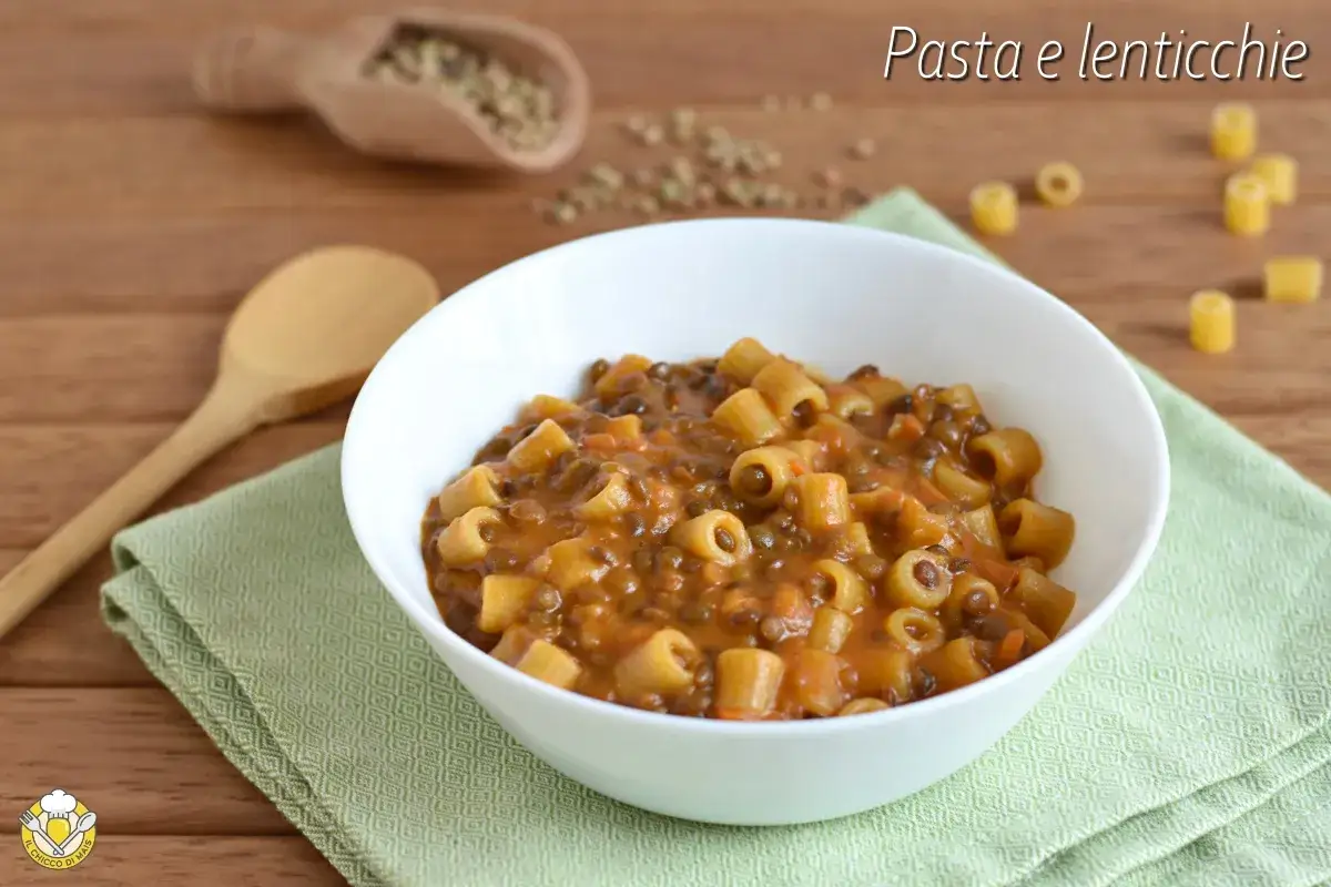 Un piatto fumante di pasta e lenticchie, un classico confortante, servito in una ciotola bianca su un tovagliolo verde.