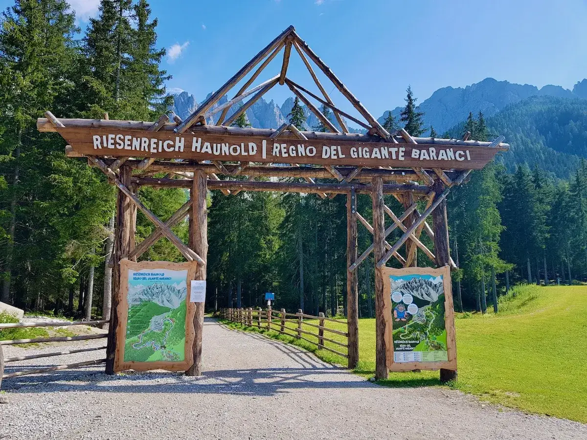 Ingresso in legno per il **Regno del Gigante Baranci**. Mappe informative e sentieri tra i boschi e le montagne.