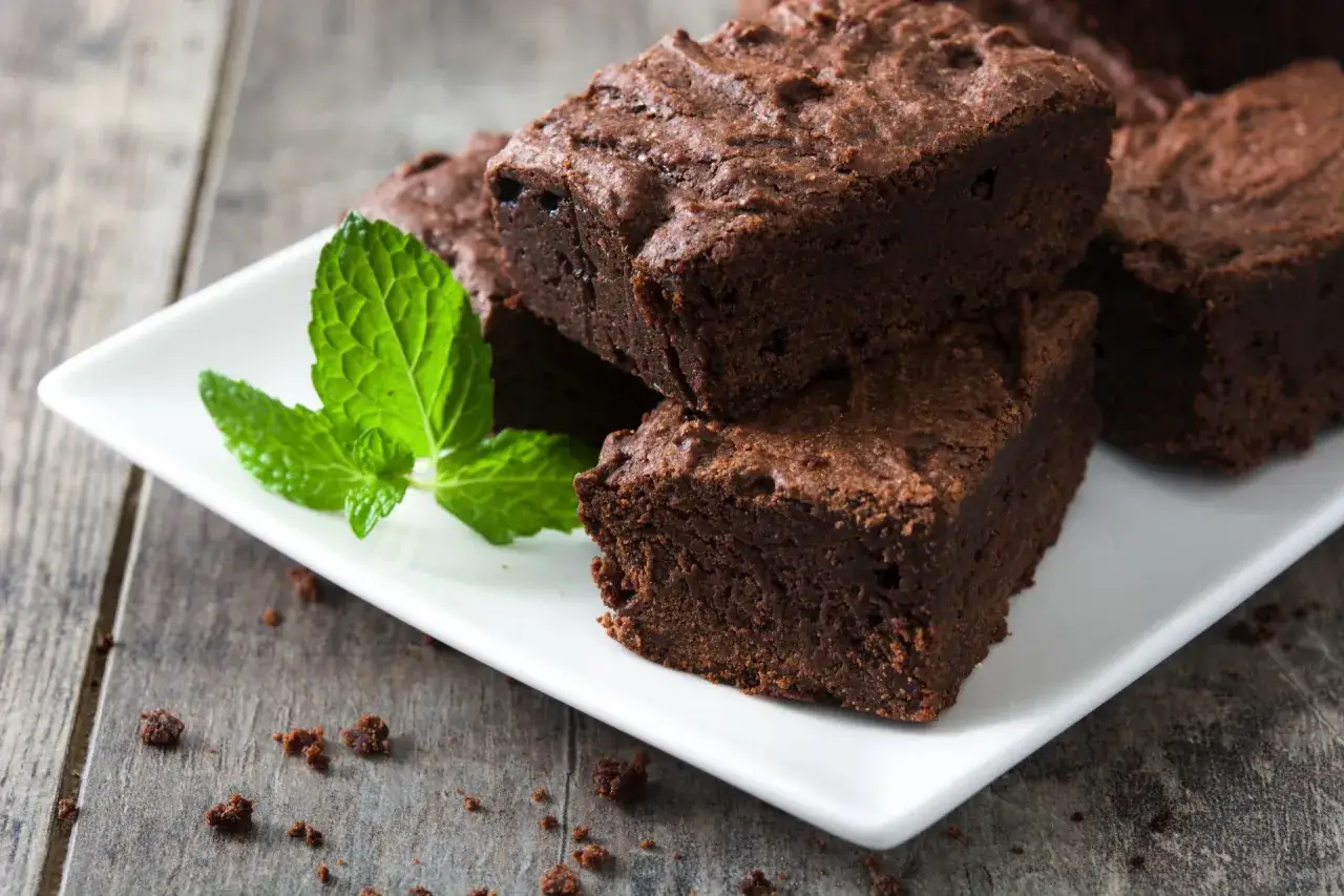 Pyszne brownie z airfryera, podane na białym talerzyku z listkiem mięty. Idealne na deser!