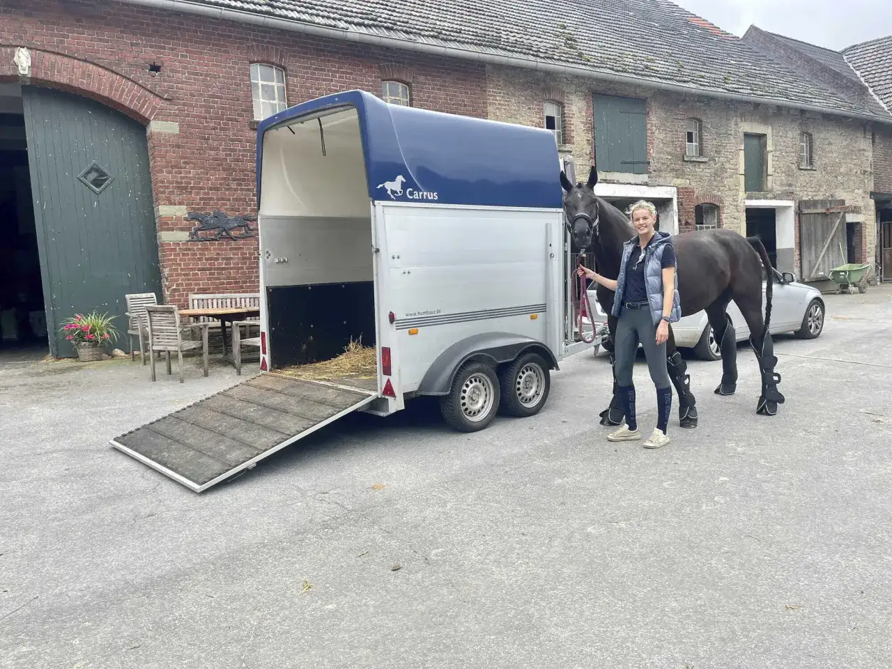 Frau mit Pferd am Anhänger, bereit für den Transport. Beachten Sie die **Pferde transportieren Vorschriften** für sicheres Reisen.