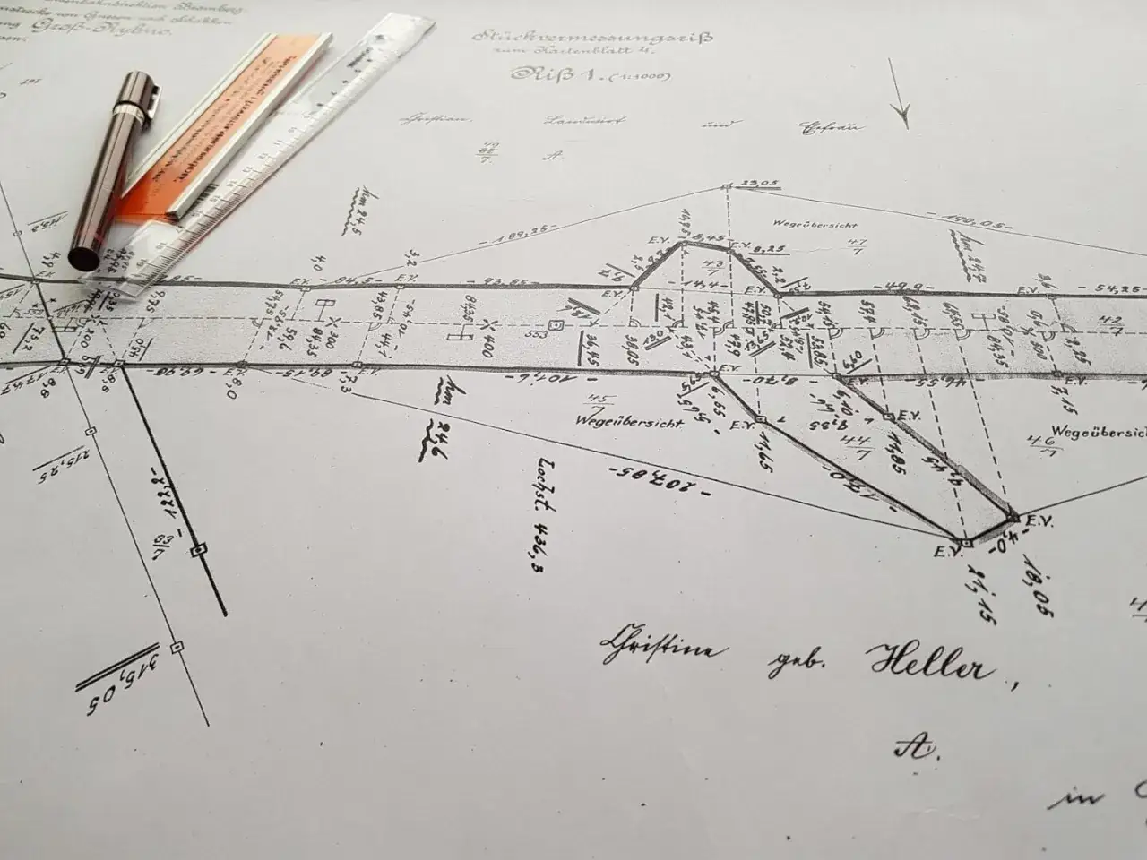 Stary plan geodezyjny z linijką i długopisem. Zastanawiasz się, ile kosztuje wyznaczenie działki przez geodetę? Ten dokument pokazuje szczegółowe pomiary.