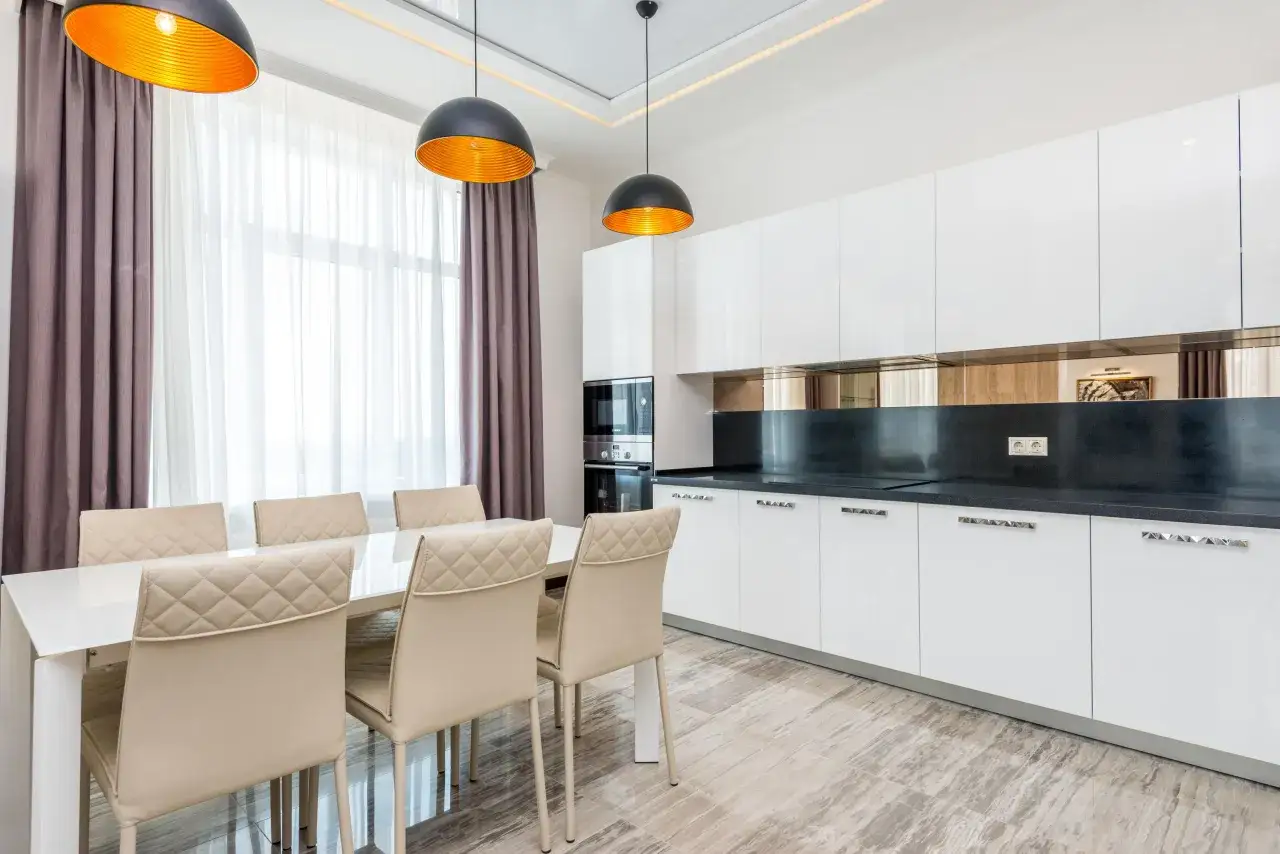 Elegantes cortinas de cocina en tonos morados y blancos, combinadas con lámparas modernas y muebles minimalistas.