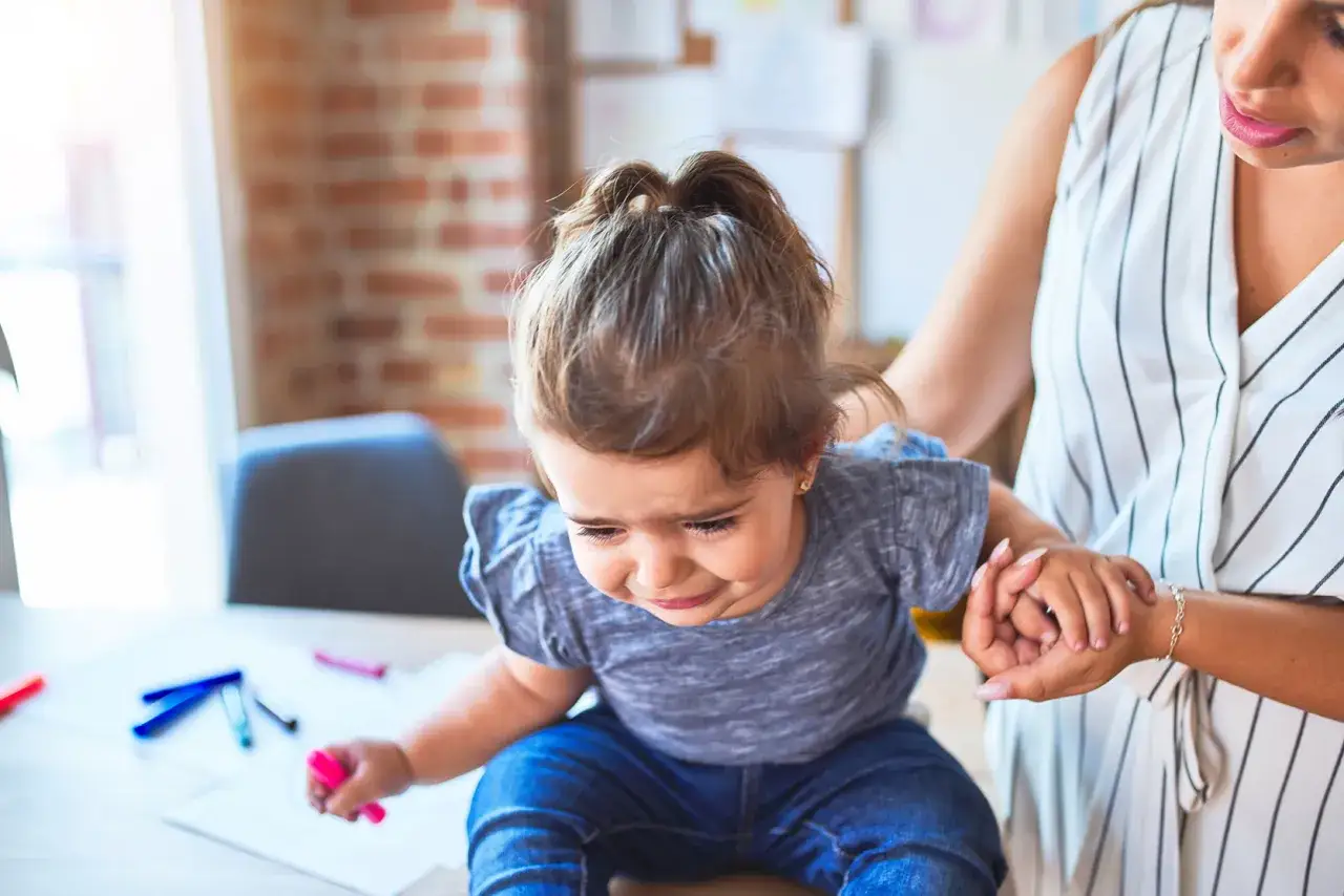 Smutne dziecko z niedoczynnością tarczycy a zachowanie. Mama wspiera córkę podczas rysowania.